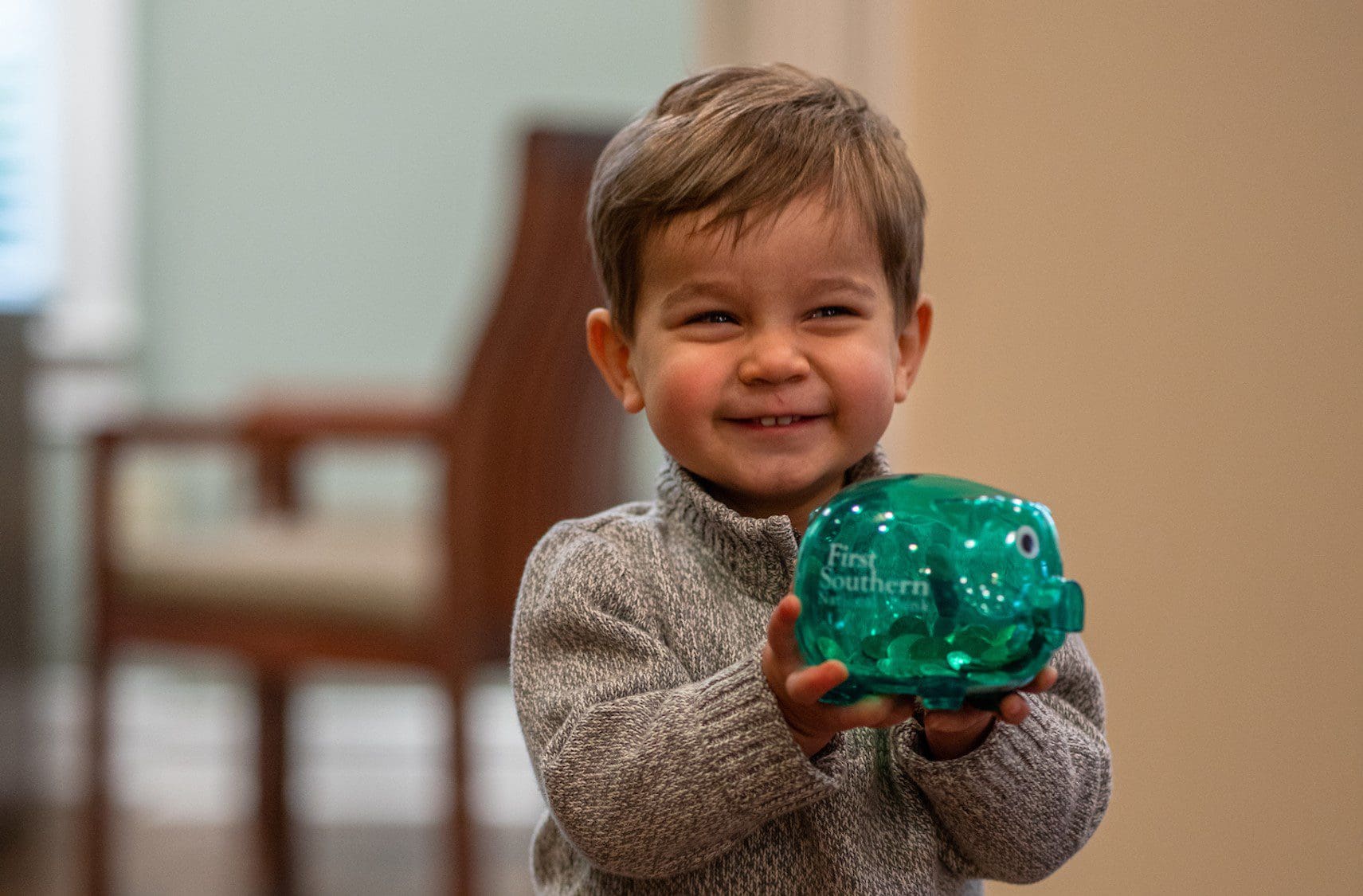 little boy holds a piggy bank with First Southern on it