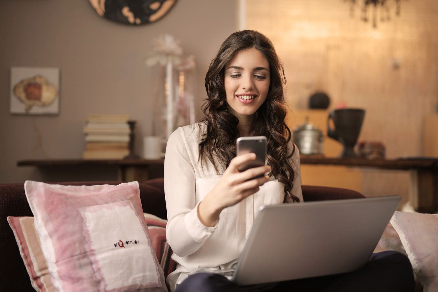 Young woman using her phone and laptop