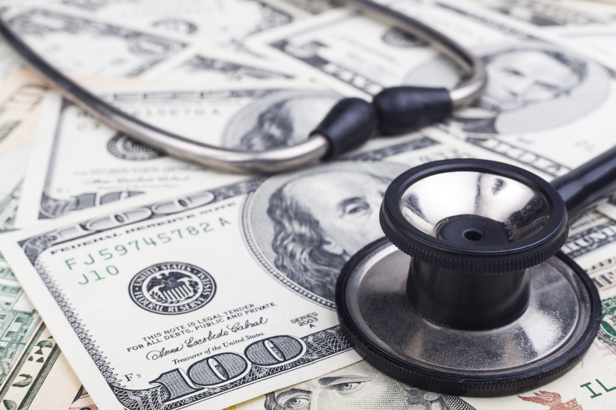 Black stethoscope close-up on top of Dollar banknotes side view